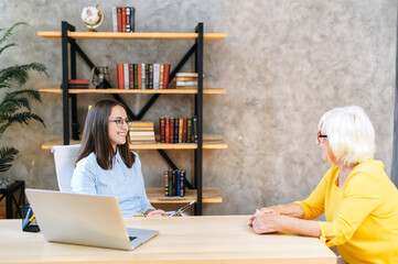 Job interview. Young female employee from hr department is interviewing senior female applicant in...