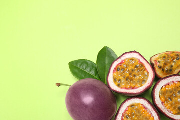 Fresh ripe passion fruits (maracuyas) with leaves on light green background, flat lay, Space for text