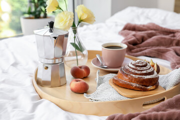 Tray with tasty breakfast on bed