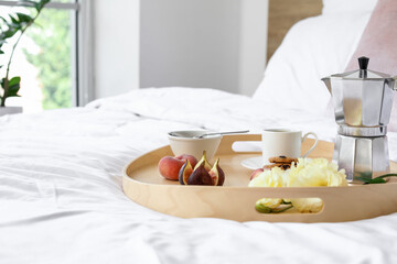 Tray with tasty breakfast on bed