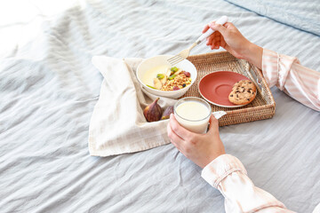 Young woman having tasty breakfast in bed