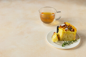 Delicious chiffon cake with custard cream and nectarines with herbal tea and thyme on light concrete background.