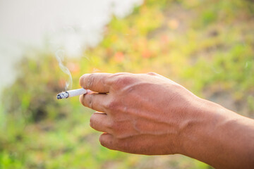 Closeup of young man hand smoking cigarette on the street.