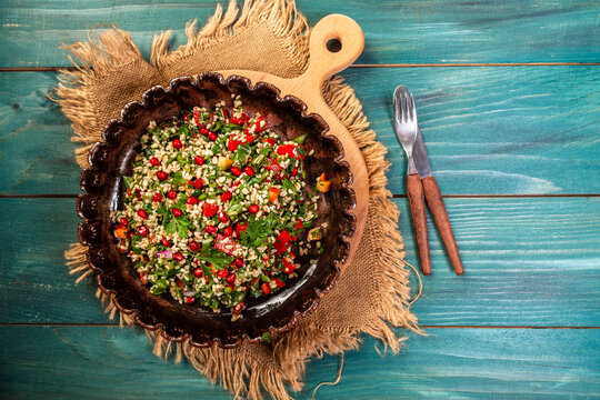 A bowl of delicious fresh tabouli with parsley, mint, tomato, onion, olive oil, lemon juice, and bulgar wheat. Traditional oriental salad Tabouleh