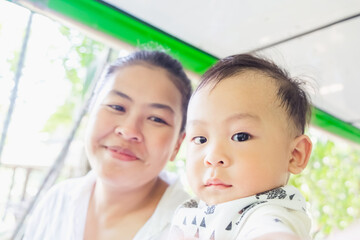 Fototapeta premium Shot of Mother and her little son sit on tram in summer day at the zoo. Concept of friendly family and vacation. Breastfeeding or early childhood development.
