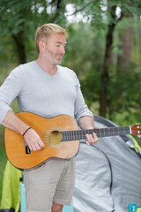 Obraz premium man playing guitar outside his tent