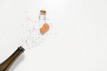 Open bottle of champagne and glitters on white background