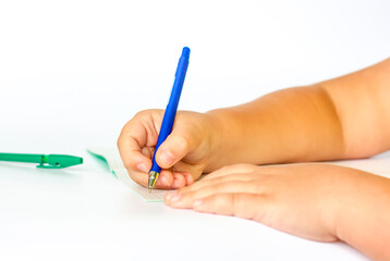 The child holds his hands over an open notebook and is going to write in it. Close-up of a child's hands.