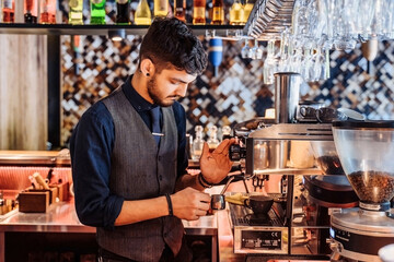 Close-up of barista making espresso from a coffee machine in a restaurant, bar or pub. Professional coffee brewing. Latte art with espresso machine steam in cafe. Vintage color tone