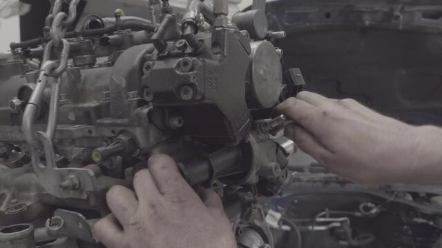Car mechanic unscrewing spark plugs. a repairman's hand fixing crashed car motor