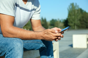 Obraz na płótnie Canvas Man using modern mobile phone outdoors, closeup