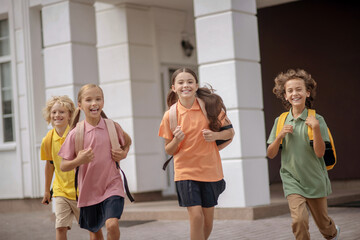 Schoolchildren with backpacks running home after lessons