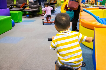 Happy toddler child boy learning to ride bicycle at the indoor playground center. Active kid...