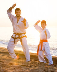 Man and boy in karate uniform training at sunny seaside