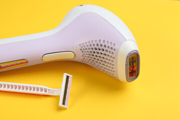 Modern photoepilator and shaving razor on yellow background