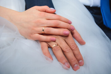 hands of bride and groom with wedding gold rings on white dress