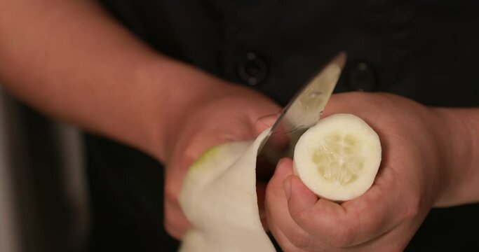 A Skilled Chef Cutting Cucumber Thinly With A Knife For A Traditional Japanese Sushi Rolls. - close up shot
