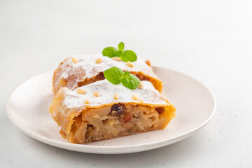 Apple strudel with raisins,  peanuts and cinnamon. South Tyrol recipe. Light background. Copy space. Minimalistic.