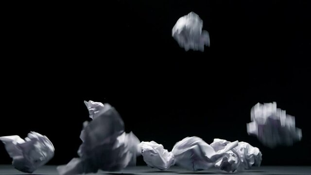 Crumpled paper falls on a black background in slow motion