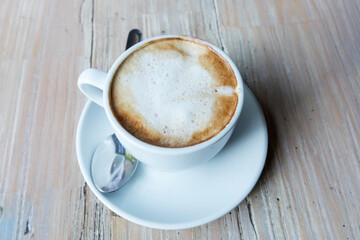 Close up hot cappuccino white coffee cup on old wood table at cafe,food and drink concept.