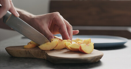 man cut fresh nectarines on a olive wood board