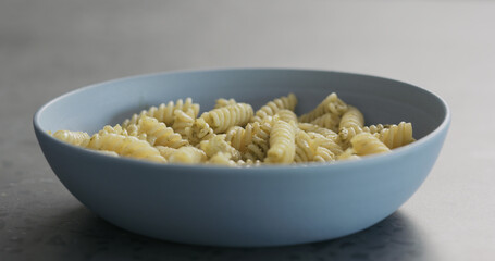 fusilli pesto pasta in blue bowl on concrete background