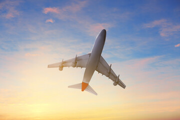 Fototapeta na wymiar Airplane flying in cloudy sky at sunset. Air transportation