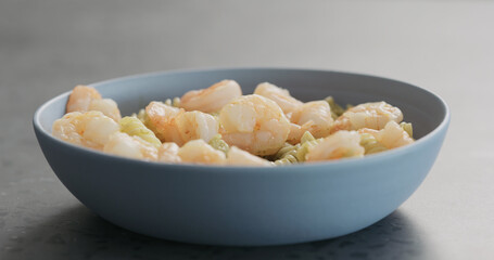pesto fusilli pasta with shrimps in blue bowl on concrete background