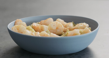 pesto fusilli pasta with shrimps in blue bowl on concrete background
