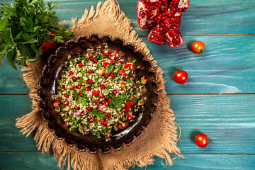 Tabbouleh salad. Traditional middle eastern or arab dish. Levantine vegetarian salad with parsley, mint, bulgur, tomatoes drizzled with lemon juice. Part of middle eastern meze. Top view