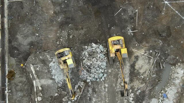Drone aerial view of worker and extractor in construction site on the ground in workplace in daylight. Busy real estate development site concept footage. Machine and industrial worker Shanghai China