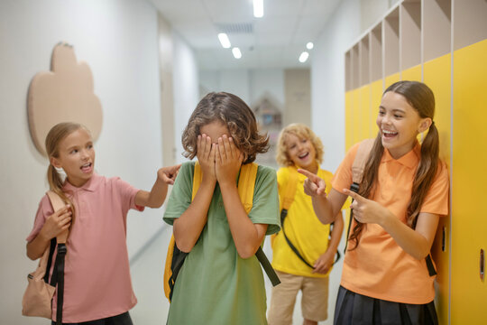 Dark-haired oy closing his face and feeling unhappy from bullying