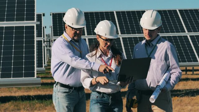Group of engineers are discussing outdoors solar panels