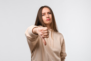 Young woman looking unhappy and angry showing dislike with thumb down, rejection concept
