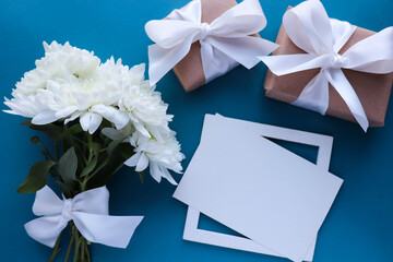postcard layout. bouquet of white chrysanthemums on a blue background and an envelope. place for text. flat lay. congratulation. invitation