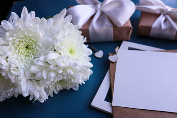 postcard layout. bouquet of white chrysanthemums on a blue background and an envelope. place for text. flat lay. congratulation. invitation