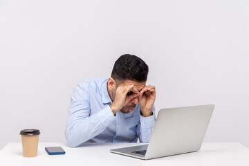Amazed male office employee looking at laptop screen through binoculars hand gesture expressing big surprise