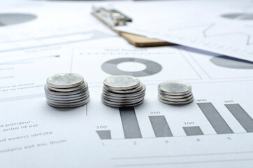 Closeup of three stacks of silver coins on the graphs and business charts.Concept of financial analyzing of budget and sales