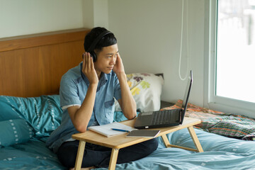 Asian student wearing headset while study through online lesson at home.