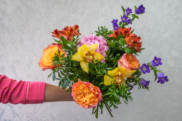 Woman's hand holds a bouquet of different flowers, wedding and gift concept, close up