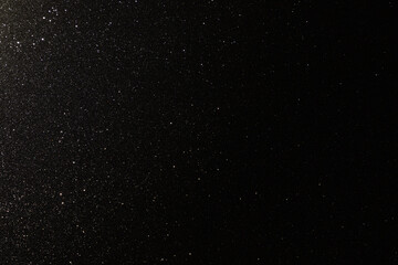 Black texture with micro-relief and glitter similar to the night sky with stars