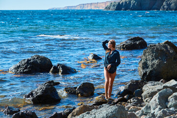 Female enjoying ocean view. Virgin nature and seascape. Sharp rocky terrain. Relax time and meditation nature concept
