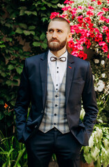 Portrait of a bearded guy in a blue suit holding his hands in his pockets