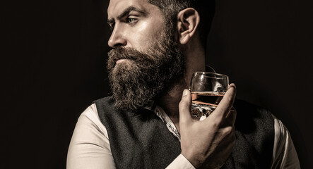 Sipping whiskey. Portrait of man with thick beard. Macho drinking. Man with beard holds glass brandy. Bearded drink cognac. Man holding a glass of whisky