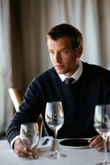 Handsome businessman dressed in the suit drinking wine. Businessman enjoying in the restaurant