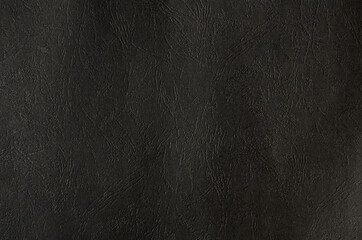 The dark texture of a  rough plastic surface with indented veins.