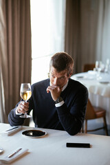 Handsome businessman dressed in the suit drinking wine. Businessman enjoying in the restaurant