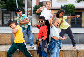 Positive girls and boys training hip hop on city street, outdoor dance class for kids