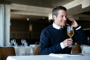 Handsome businessman dressed in the suit drinking wine. Businessman enjoying in the restaurant.