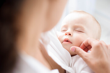 Baby sleeping on the mother's chest. Young mother cuddling baby